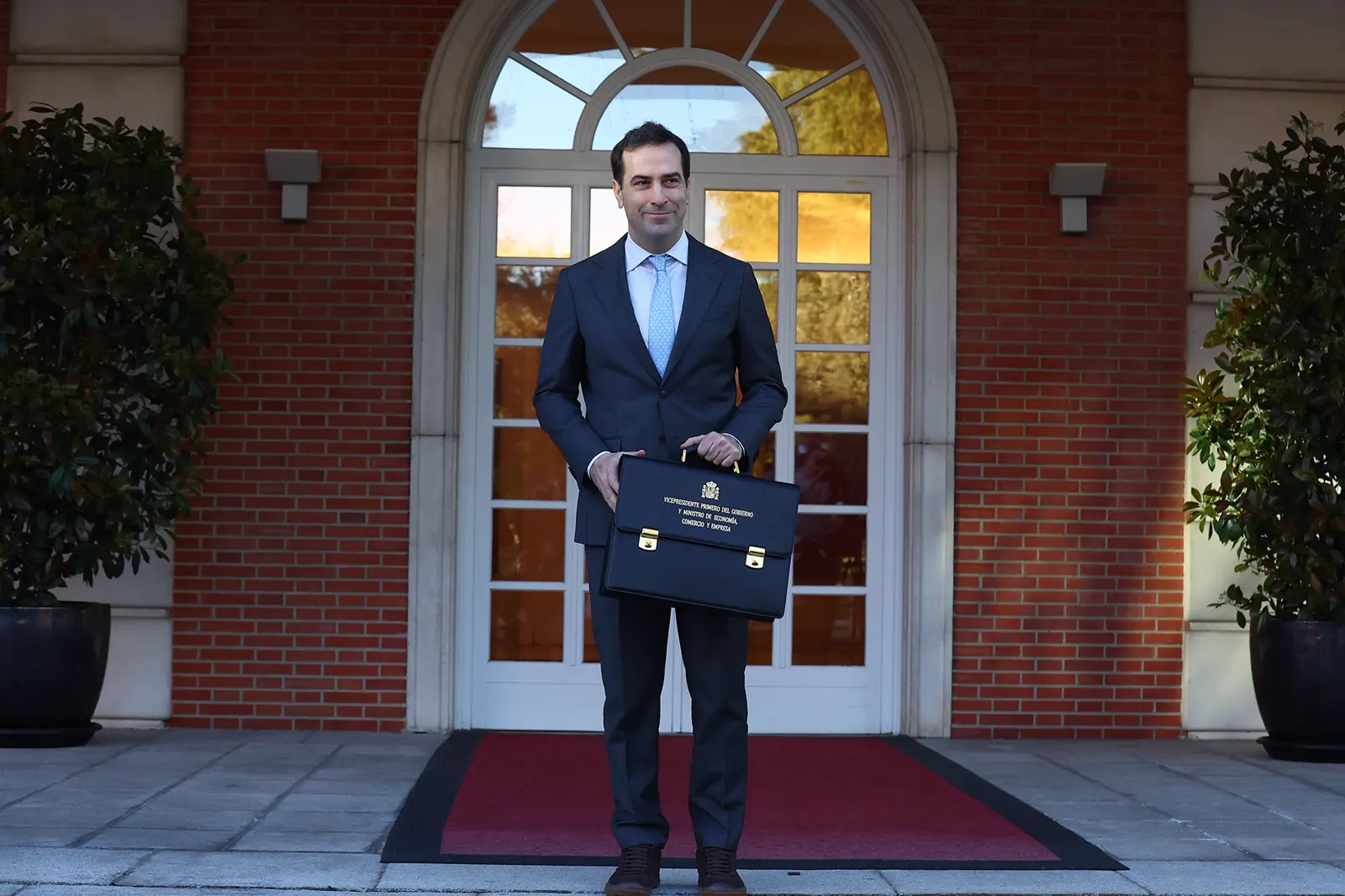 Carlos Cuerpo, con traje oscuro y una cartera de mano, posa de pie en la escalinata del edificio del Consejo de Ministros, en el complejo de La Moncloa.