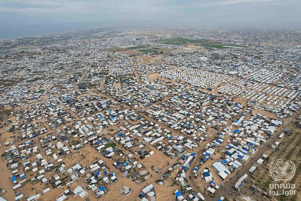 Vista aérea de miles de tiendas de campaña blancas y refugios improvisados que cubren la zona de Al Mawasi hasta la línea de costa, bajo un cielo gris