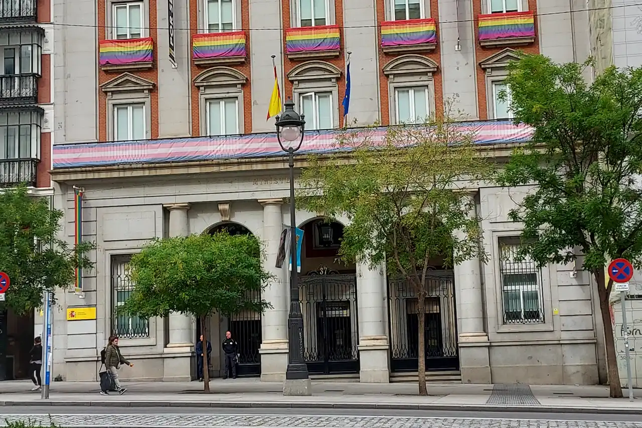 Fachada y entrada de la sede del Ministerio de Igualdad en Madrid, con las banderas de España y de la Unión Europea sobre el portalón y balcones con banderas arcoíris
