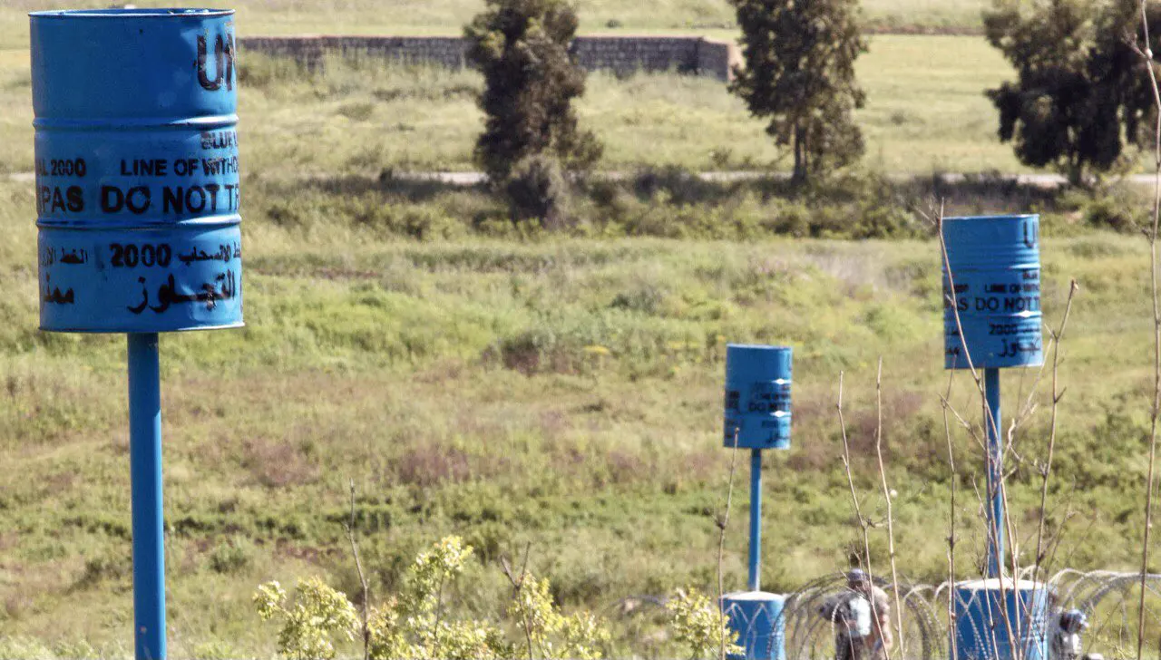 Bidones azules de la ONU con la inscripción «línea de retirada, no pasar» plantados entre la vegetación y alambre de espino en el sur del Líbano