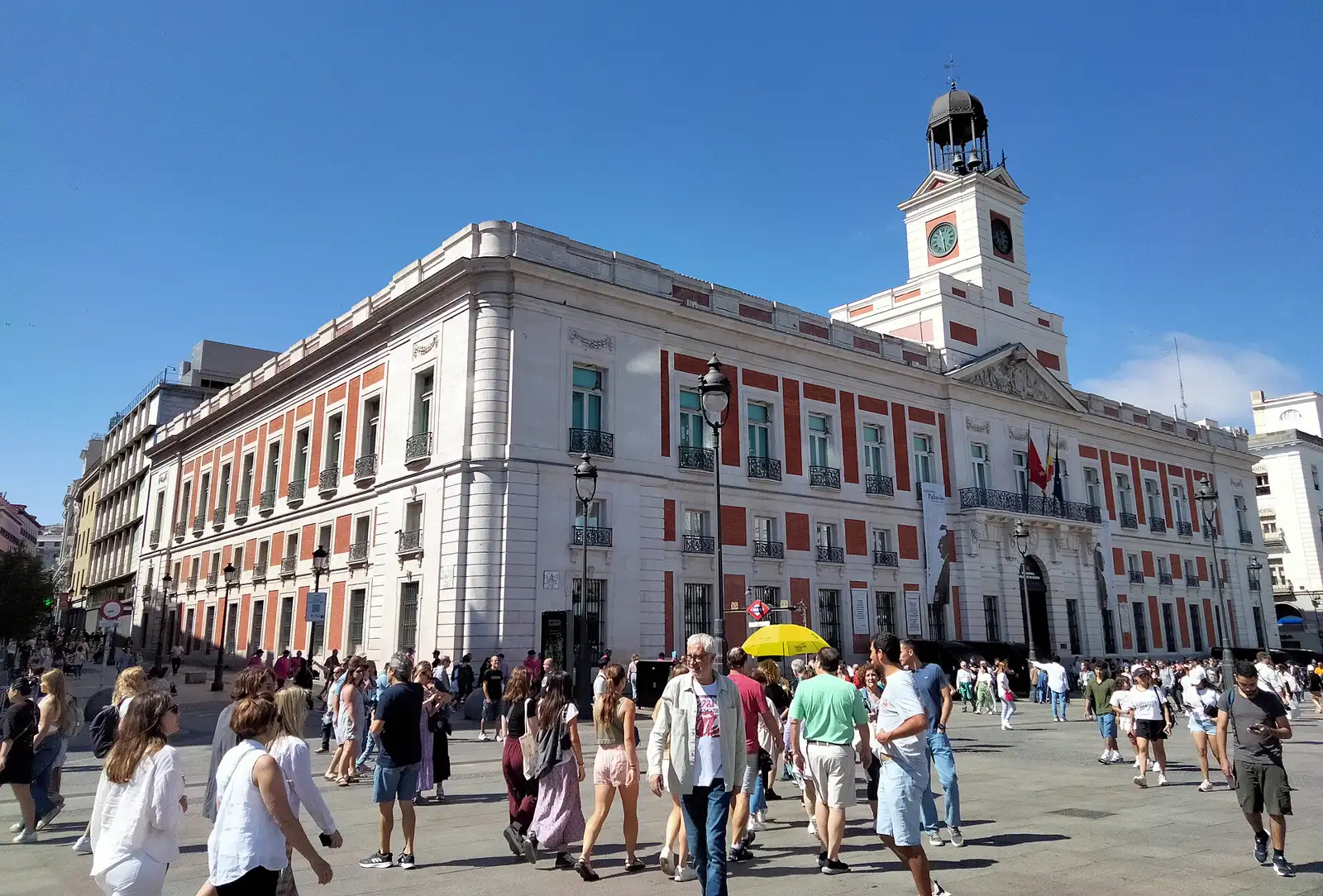 Fachada de la Real Casa de Correos, con su torre del reloj, y decenas de viandantes en la Puerta del Sol de Madrid