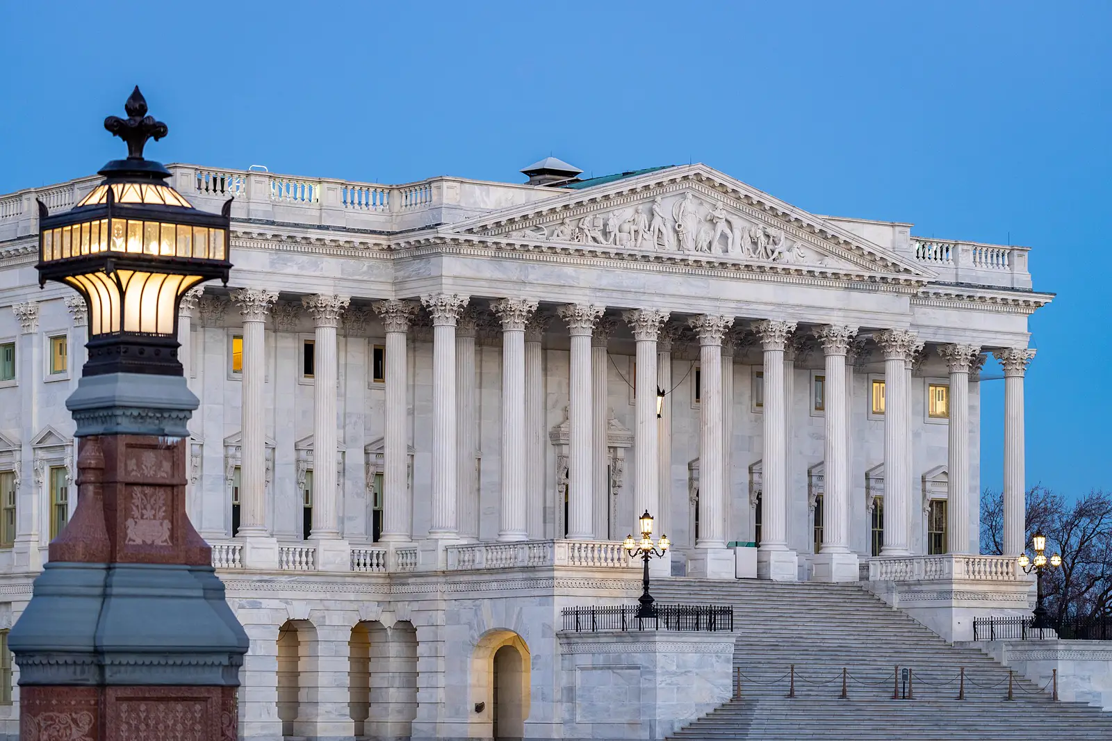 Fachada del ala del Senado en el Capitolio de Estados Unidos al atardecer, con una farola encendida en primer plano