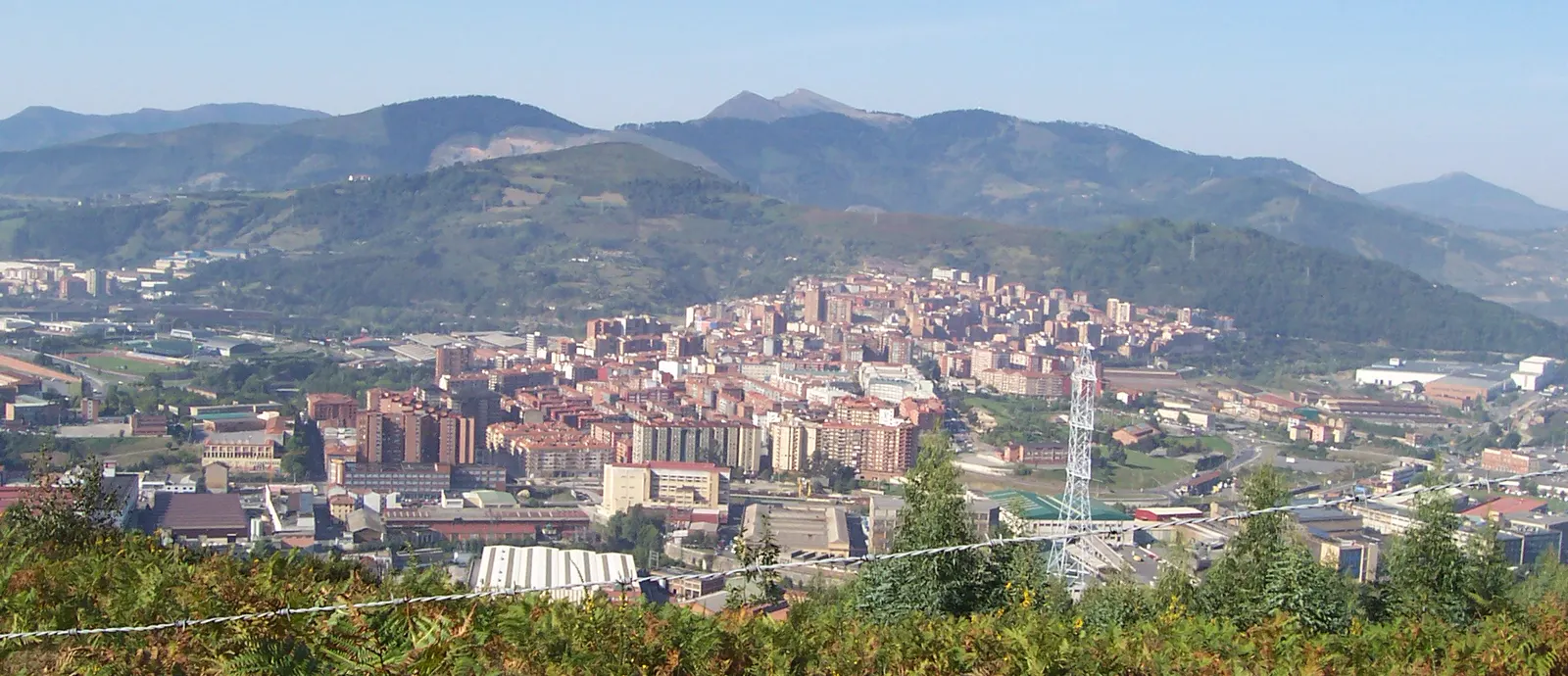 Vista aérea de Basauri, con bloques de viviendas de varias alturas apiñados en el valle entre montes y polígonos industriales