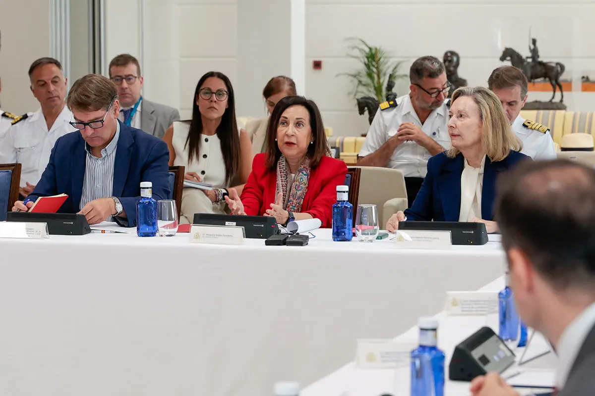 La ministra de Defensa, Margarita Robles, habla sentada a una mesa larga junto a cargos civiles y oficiales de la Armada durante una reunión.
