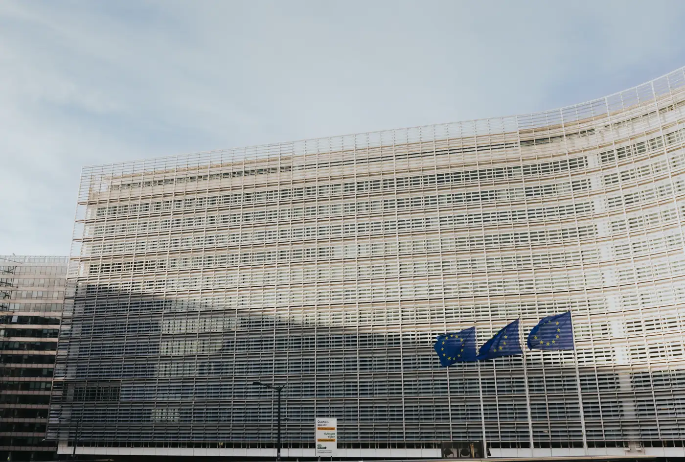 Fachada del edificio Berlaymont, sede de la Comisión Europea en Bruselas, con tres banderas de la Unión Europea ondeando delante