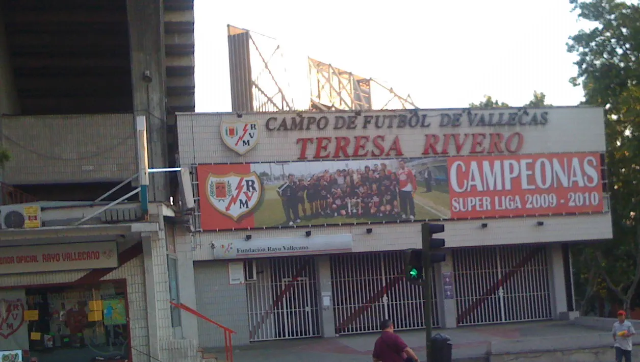 Fachada exterior del estadio del Rayo Vallecano con el rótulo «Campo de Fútbol de Vallecas - Teresa Rivero», las verjas de acceso cerradas y la tienda oficial del club a la izquierda.