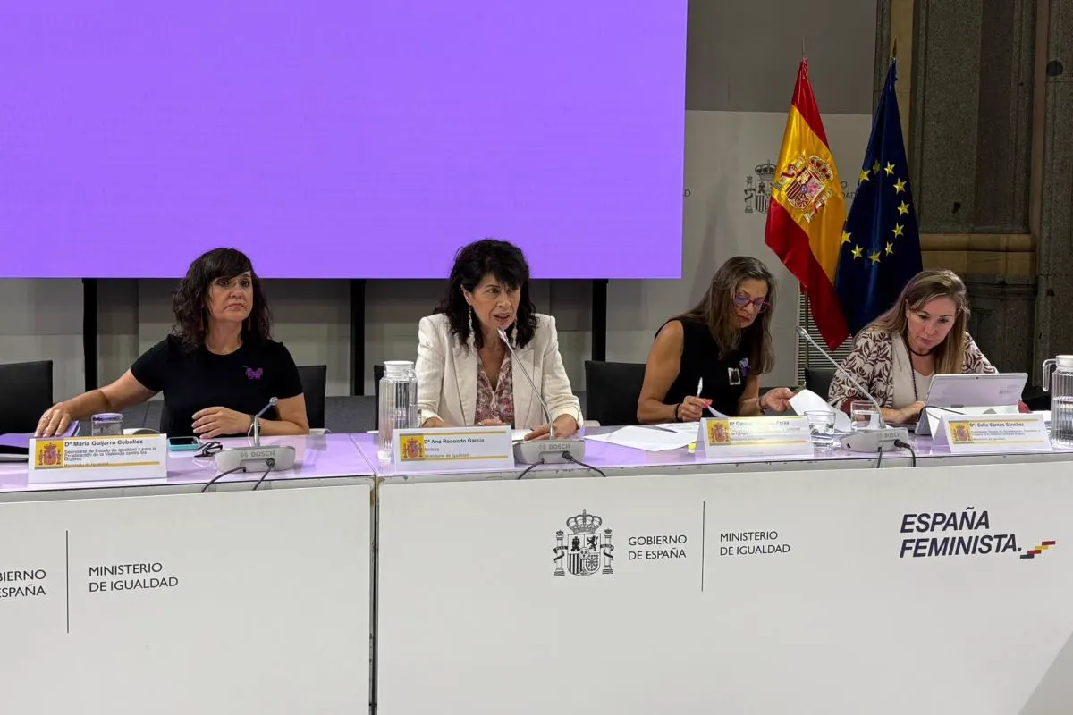 Cuatro mujeres sentadas tras una mesa presidencial con el rótulo «Gobierno de España. Ministerio de Igualdad»; la segunda por la izquierda habla ante un micrófono, con banderas de España y de la Unión Europea al fondo