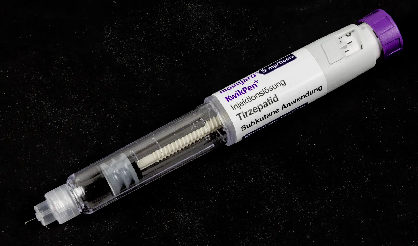 Pluma precargada blanca y azul del medicamento Mounjaro (tirzepatida) de Lilly, de 5 miligramos por dosis, junto a su caja de cartón, sobre fondo claro.