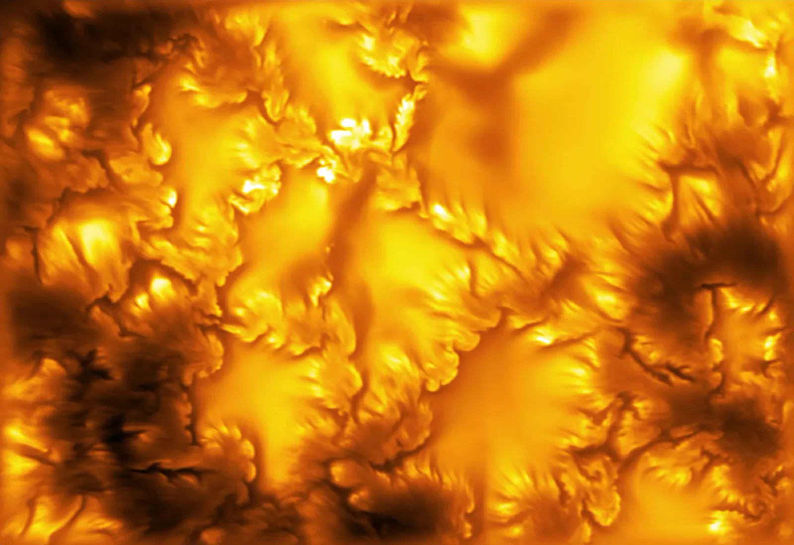 Superficie del Sol en tonos anaranjados y dorados, con estructuras filamentosas brillantes separadas por surcos oscuros y bordes deshilachados en forma de pequeños remolinos.
