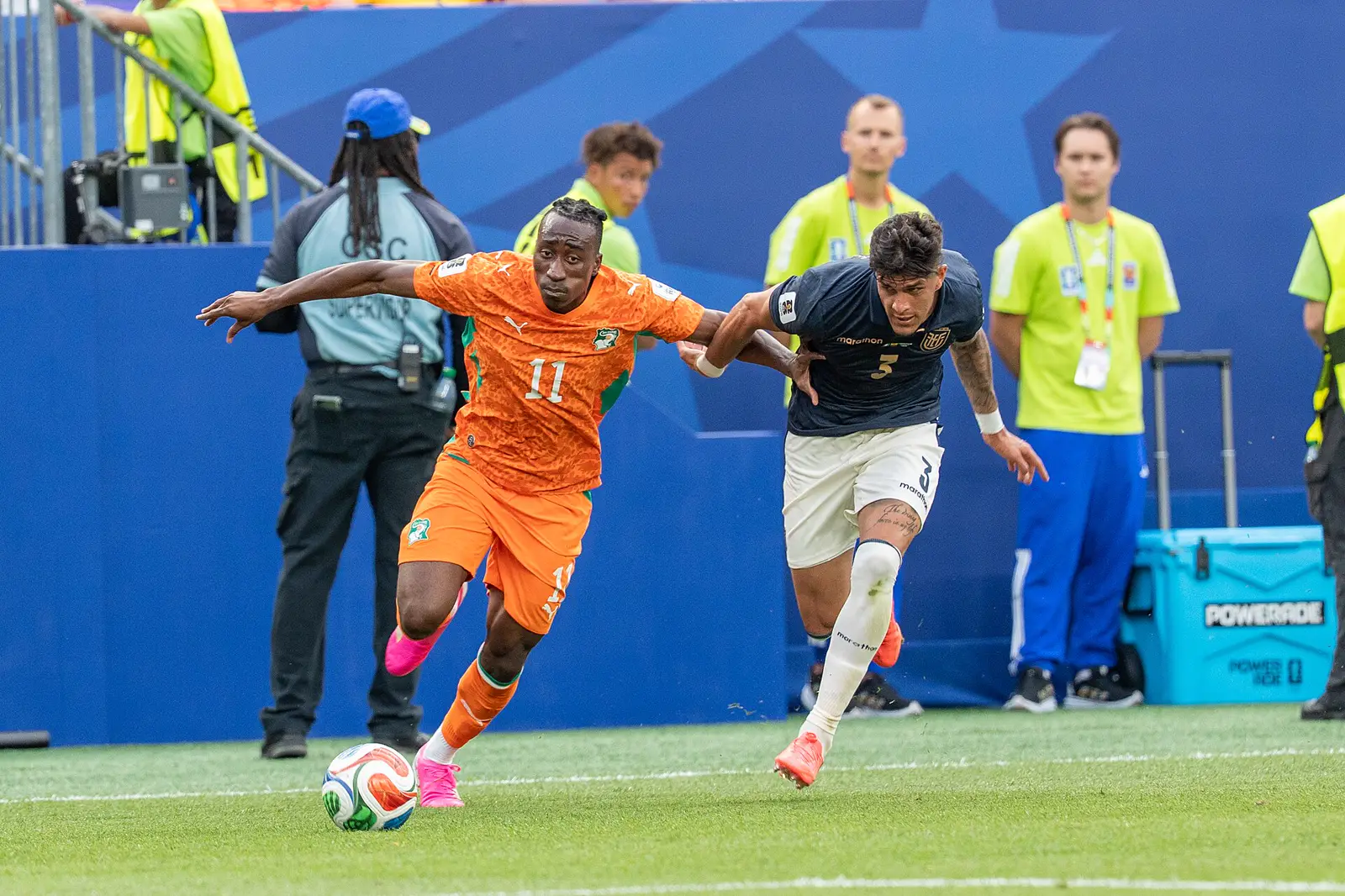 Yan Diomande, con la camiseta naranja número 11 de Costa de Marfil, conduce el balón perseguido por un jugador de Ecuador durante un partido del Mundial