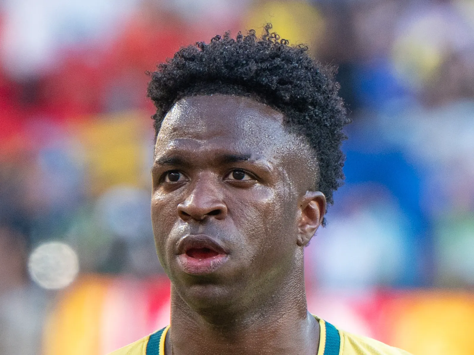 Primer plano de Vinícius Júnior, con la camiseta amarilla de la selección de Brasil, mirando al frente en el terreno de juego