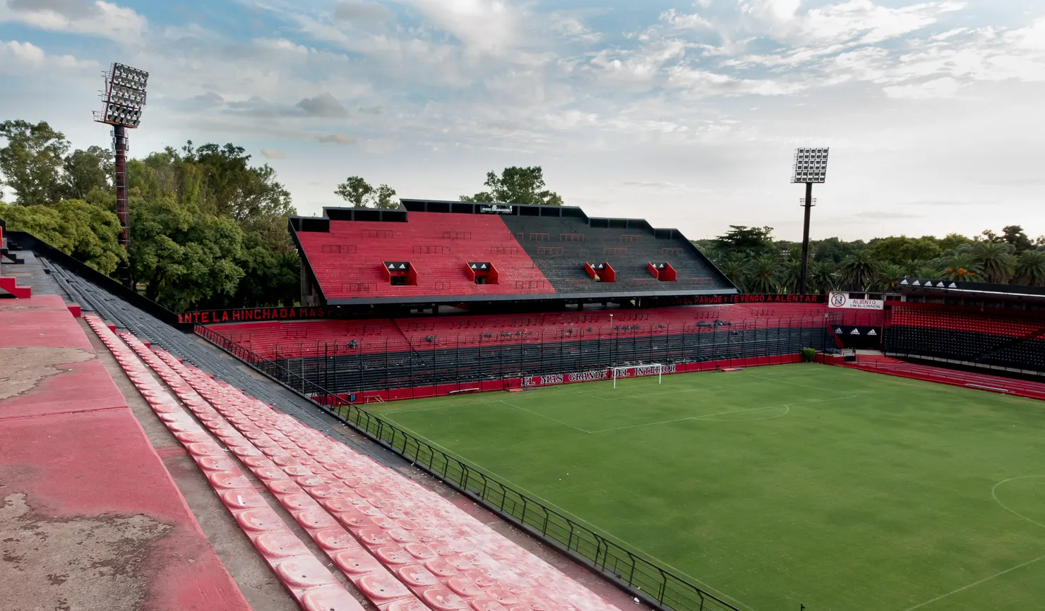 Gradas vacías rojas y negras del estadio Marcelo Bielsa de Newell's Old Boys, en Rosario, con el césped a la derecha