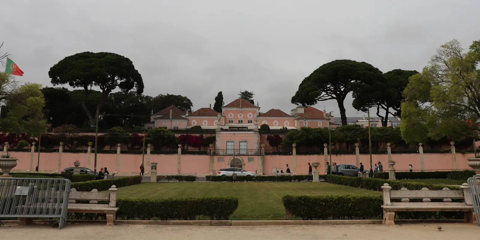 Fachada rosada del Palacio Nacional de Belém, en Lisboa, vista desde el jardín, con la bandera portuguesa ondeando a la izquierda
