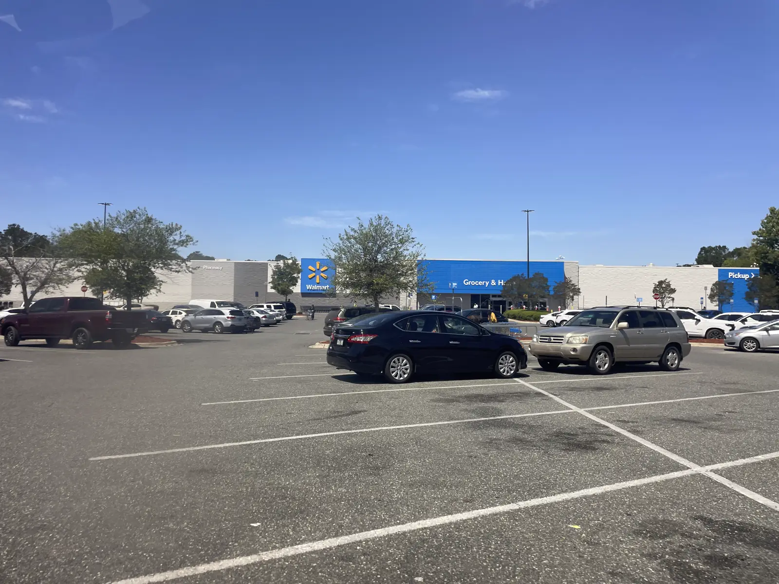 Exterior de un hipermercado Walmart Supercenter, con el logotipo de la cadena sobre la fachada azul y blanca y coches en el aparcamiento.