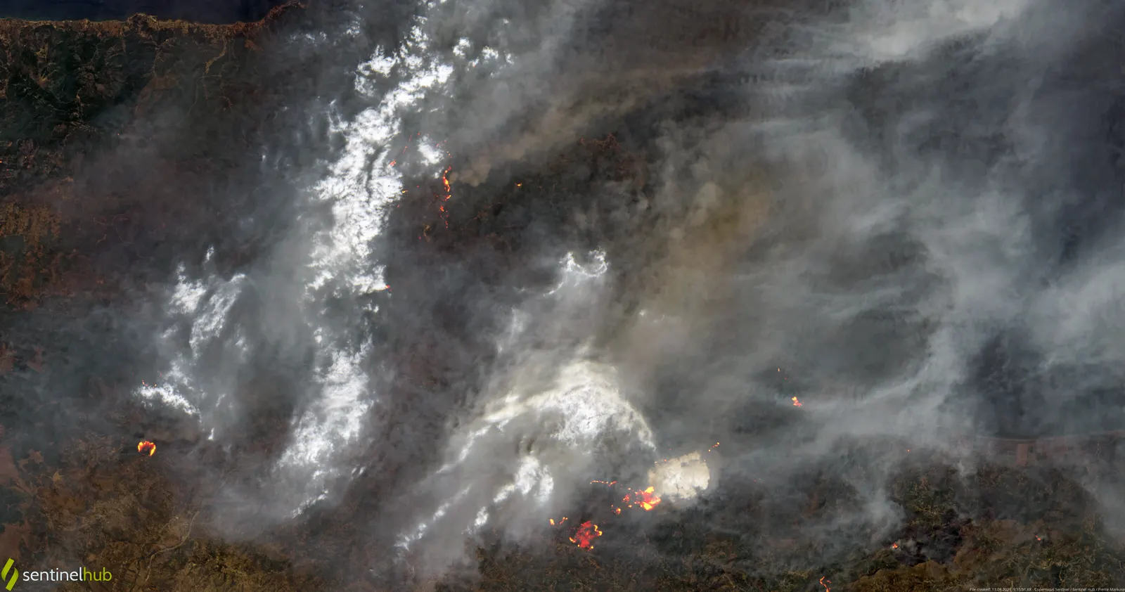 Imagen de satélite del norte de Argelia: una gran columna de humo gris cubre la franja montañosa junto a la costa y en el interior se distinguen varios frentes de llamas anaranjados sobre el terreno quemado