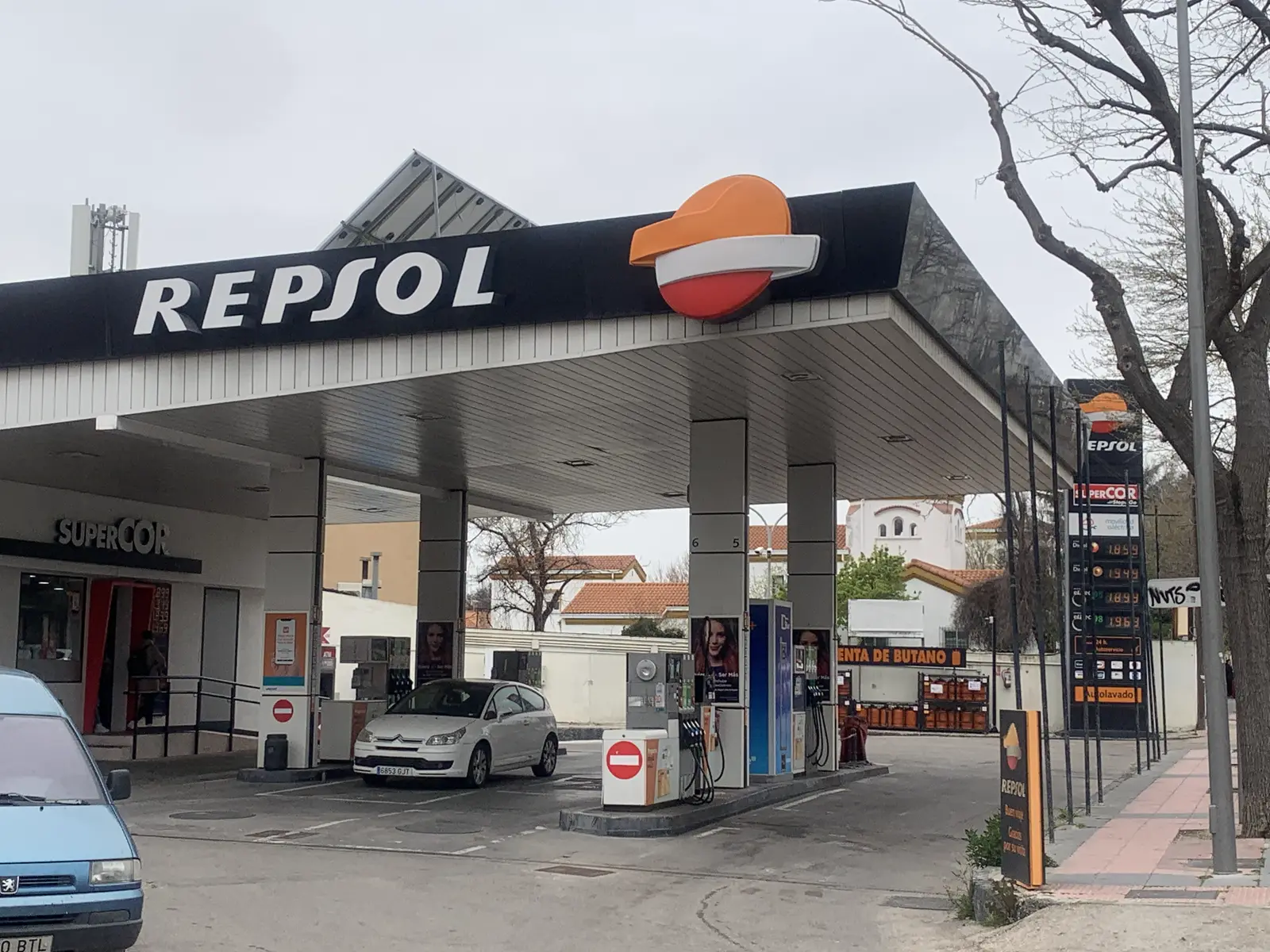 Estación de servicio Repsol con la marquesina y el rótulo de la marca sobre los surtidores, un coche aparcado junto a un poste de repostaje y, a la derecha, el tótem con los precios del litro de carburante.