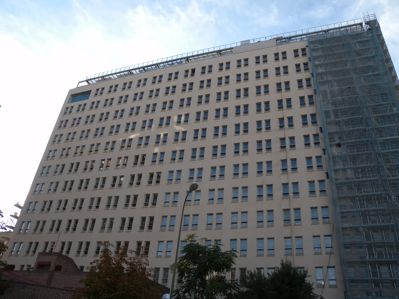 Fachada del edificio de oficinas de la sede de Isdefe en la calle Beatriz de Bobadilla de Madrid, con andamios en un lateral