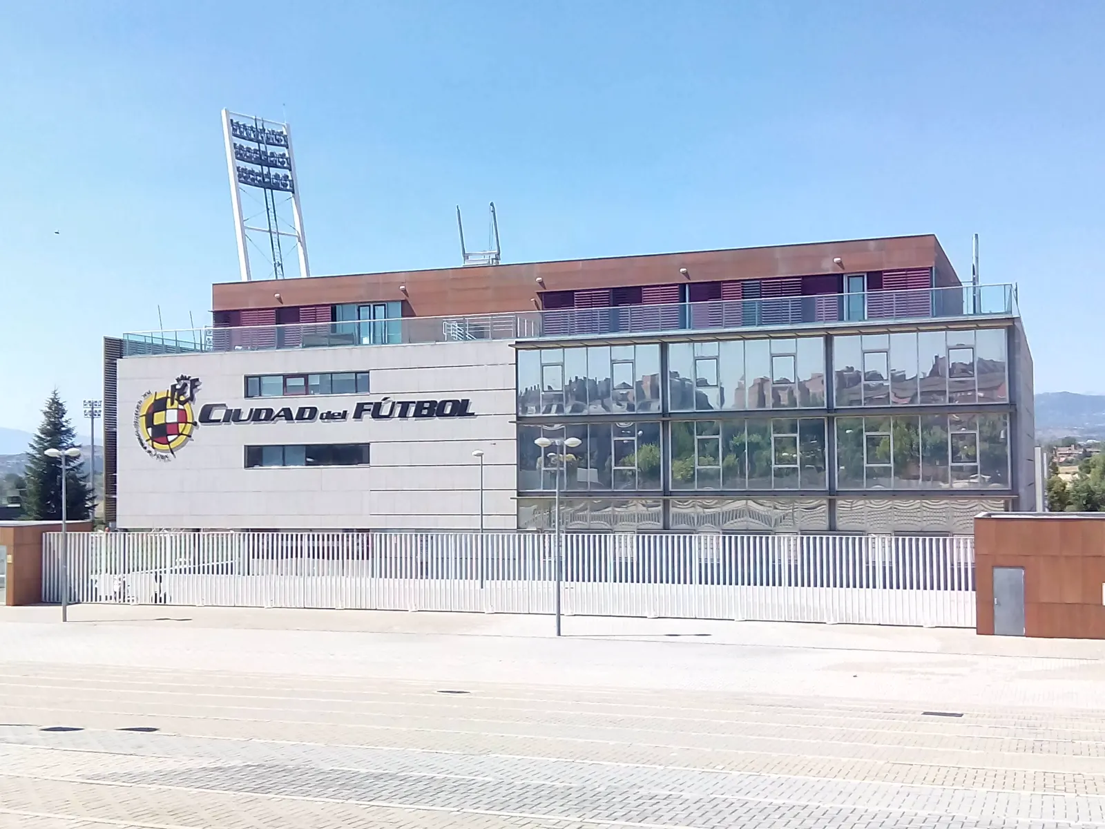 Edificio de la Ciudad del Fútbol de Las Rozas, con el escudo de la Real Federación Española de Fútbol y el rótulo «Ciudad del Fútbol» en la fachada, bajo un cielo despejado.
