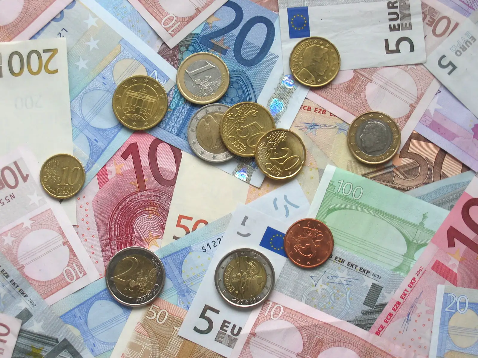 Billetes de euro de 5, 10, 20, 50, 100 y 200 extendidos sobre una superficie, con monedas de 1 y 2 euros y de 5, 10 y 20 céntimos encima.