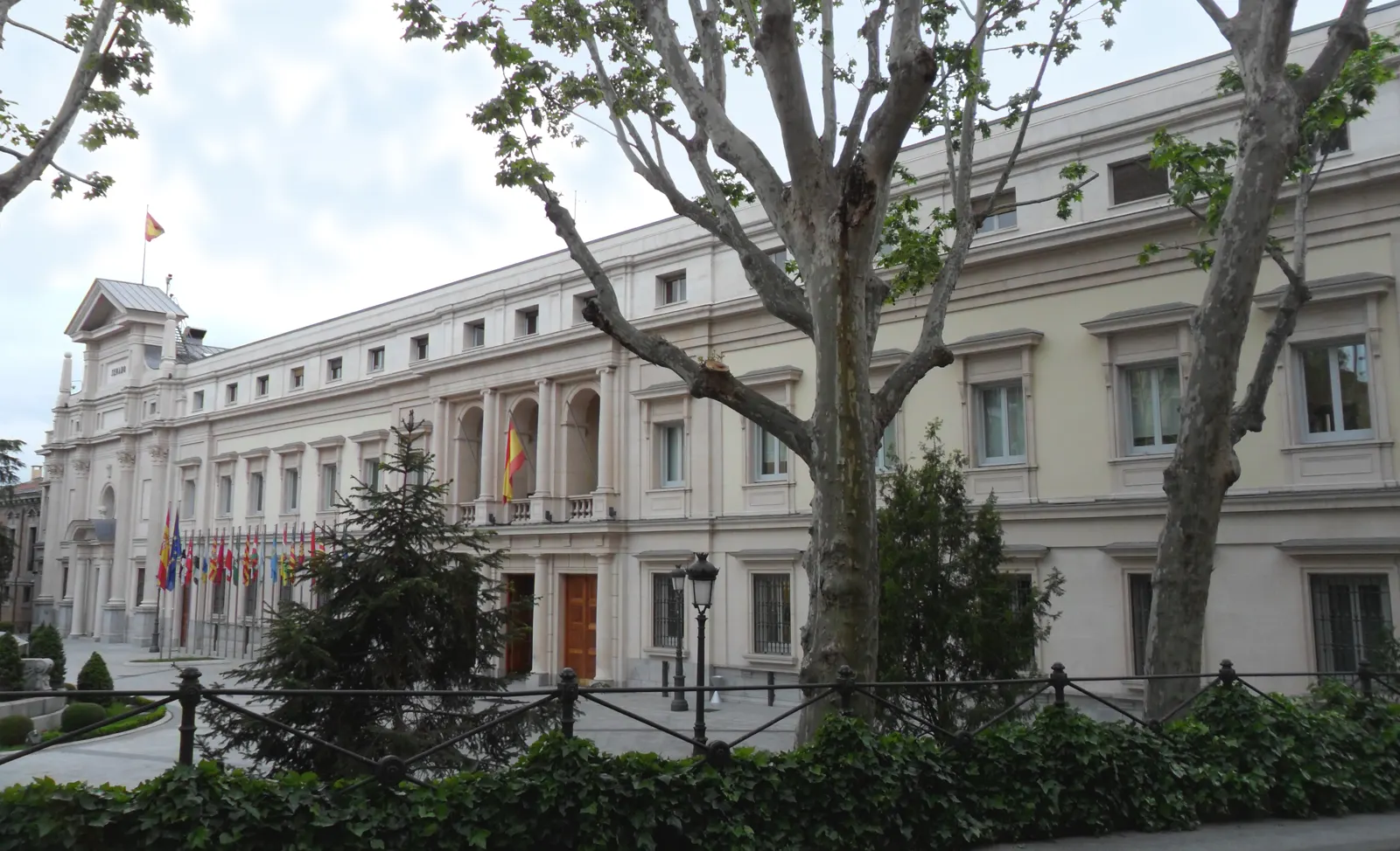 Fachada principal del Palacio del Senado, en Madrid, con su pórtico de columnas y la bandera de España