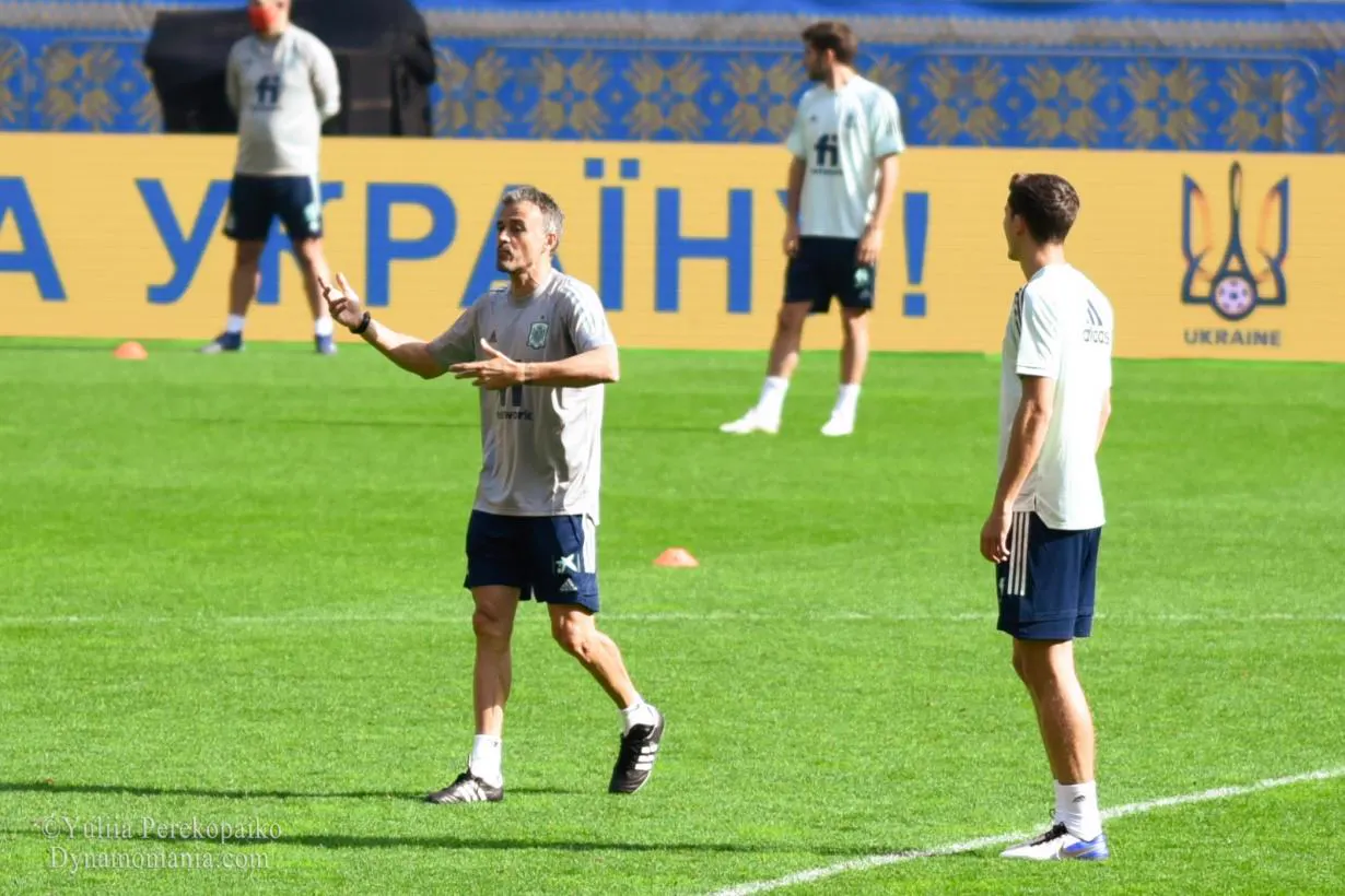 Luis Enrique, con chándal de la selección española, gesticula con las manos mientras da instrucciones a un jugador durante un entrenamiento sobre césped