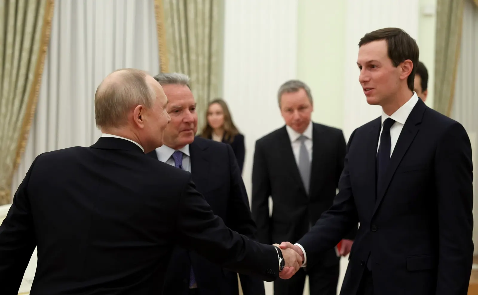 Vladímir Putin, de espaldas, estrecha la mano de Jared Kushner en una sala del Kremlin de cortinajes claros; a su lado, Steve Witkoff y otros miembros de la delegación estadounidense observan.