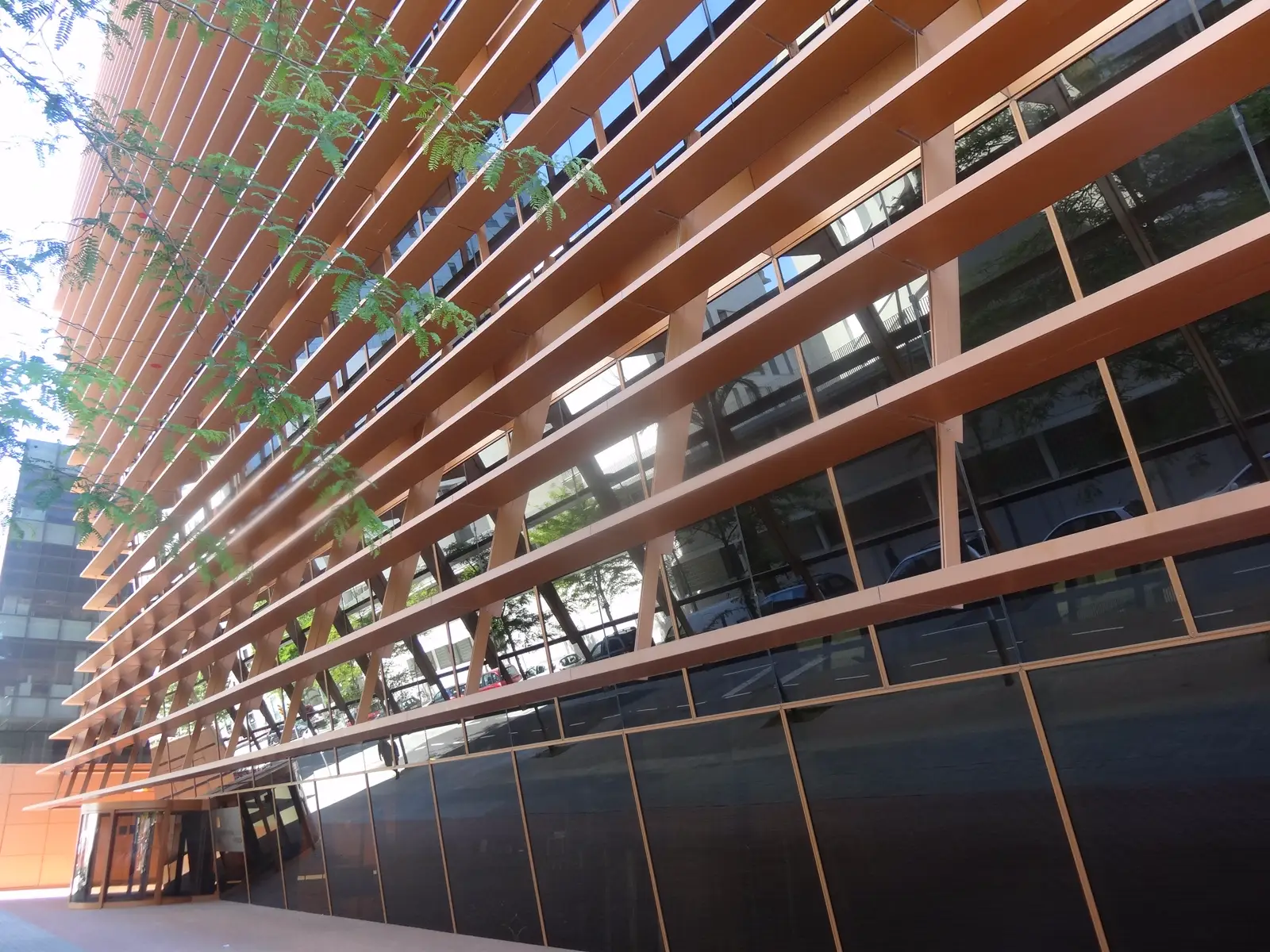 Fachada de listones de madera y vidrio del edificio de la Comisión Nacional de los Mercados y la Competencia en Barcelona, vista desde la acera.