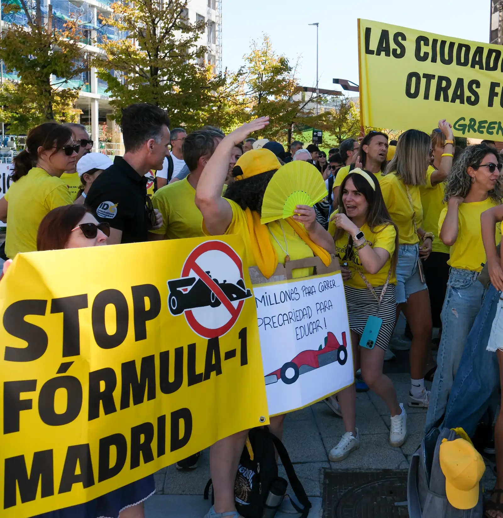 Manifestantes con camisetas amarillas sostienen una pancarta que dice «Stop Fórmula-1 Madrid», con un monoplaza tachado, junto a otra amarilla de Greenpeace con el lema «Las ciudades necesitan otras fórmulas»